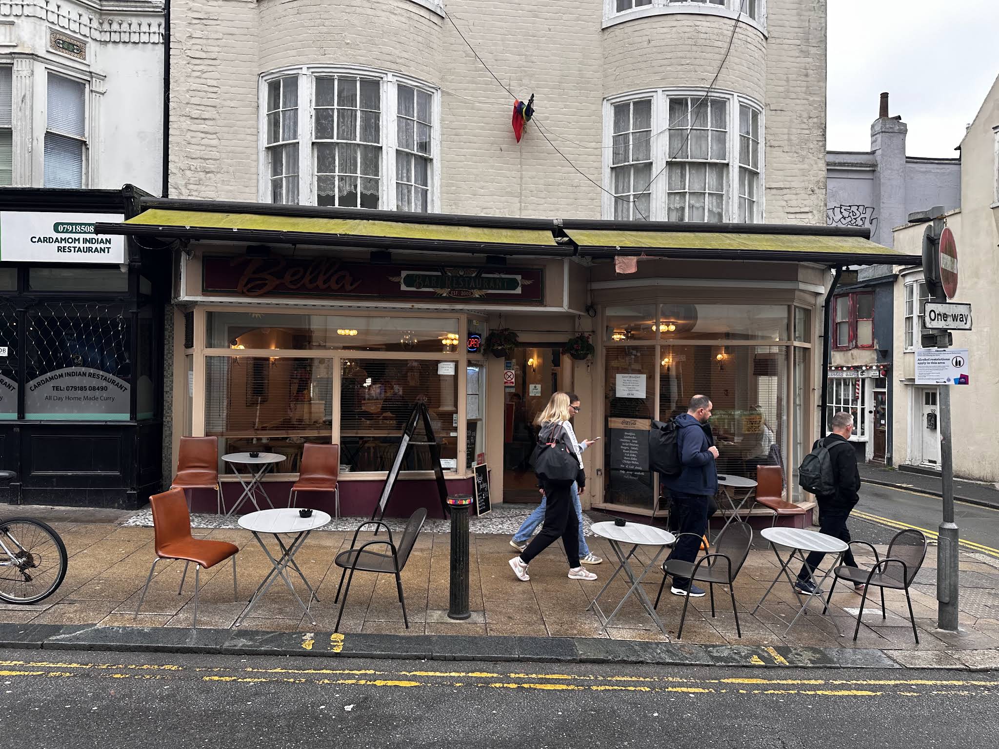 Bella Bar Restaurant's full shopfront, sign, entrance and street-side tables