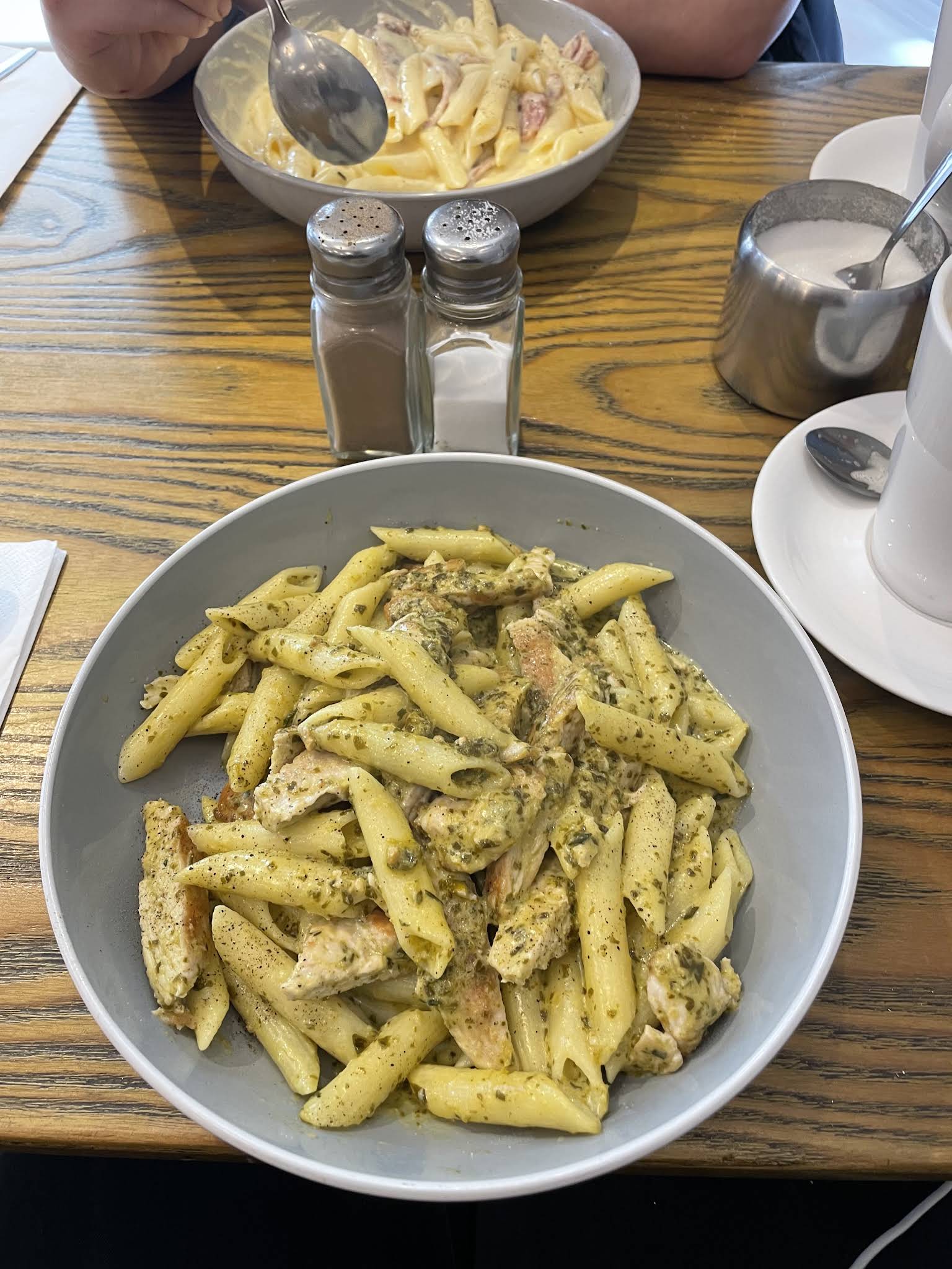 A complete bowl of penne pasta on a wooden table at Bella Bar Restaurant